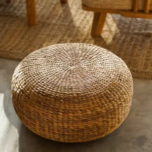 Élégant pouf tressé en fibres naturelles, présentant une texture organique riche et un design circulaire, idéal pour ajouter une assise supplémentaire ou une touche décorative à tout espace de vie contemporain